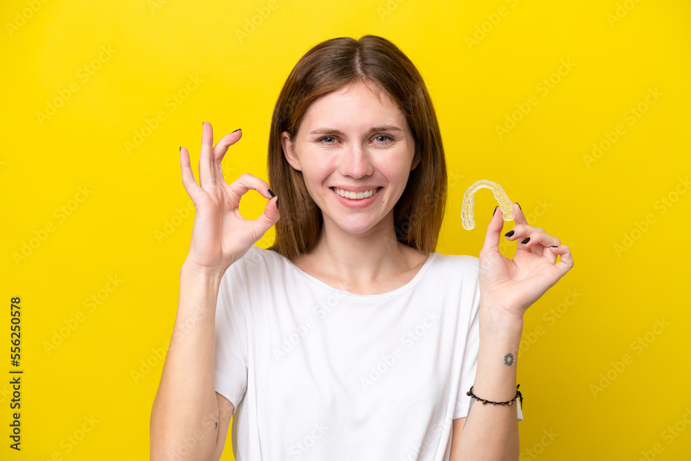 Young English woman holding invisible braces showing ok sign with fingers Young English woman holding invisible braces showing ok sign with fingers