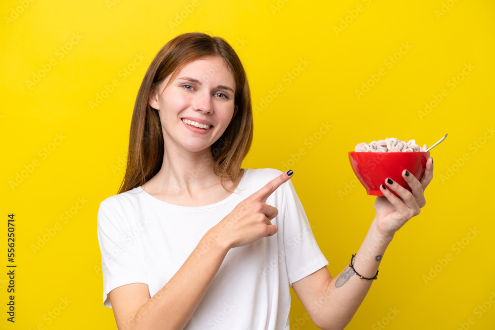 Young English woman holding cup of coffee isolated on yellow background and pointing it Young English woman holding cup of coffee isolated on yellow background and pointing it