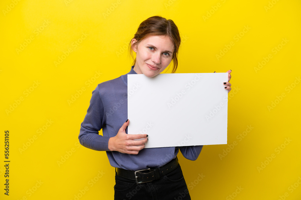 Young English woman isolated on yellow background holding an empty placard with happy expression Young English woman isolated on yellow background holding an empty placard with happy expression