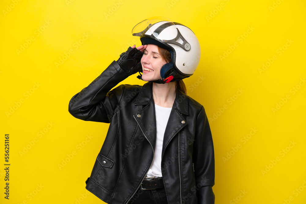 Young English woman with a motorcycle helmet isolated on yellow background smiling a lot Young English woman with a motorcycle helmet isolated on yellow background smiling a lot