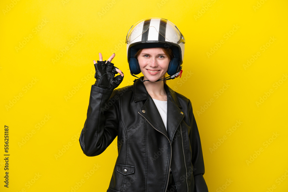 Fototapeta premium Young English woman with a motorcycle helmet isolated on yellow background showing ok sign with fingers
