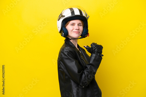 Young English woman with a motorcycle helmet isolated on yellow background proud and self-satisfied