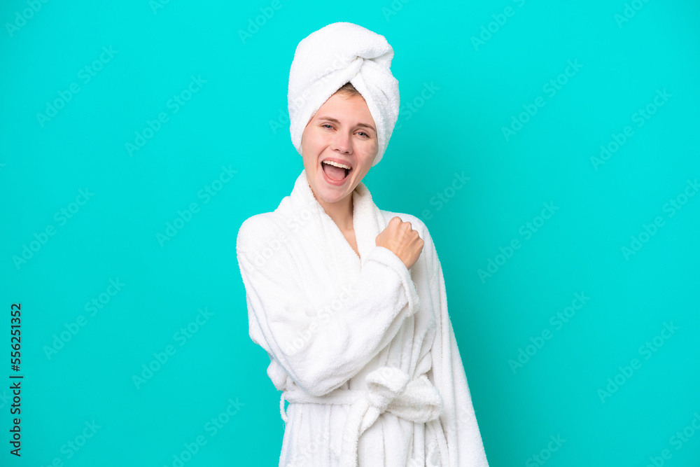 Young woman in a bathrobe isolated on blue background celebrating a victory Young woman in a bathrobe isolated on blue background celebrating a victory