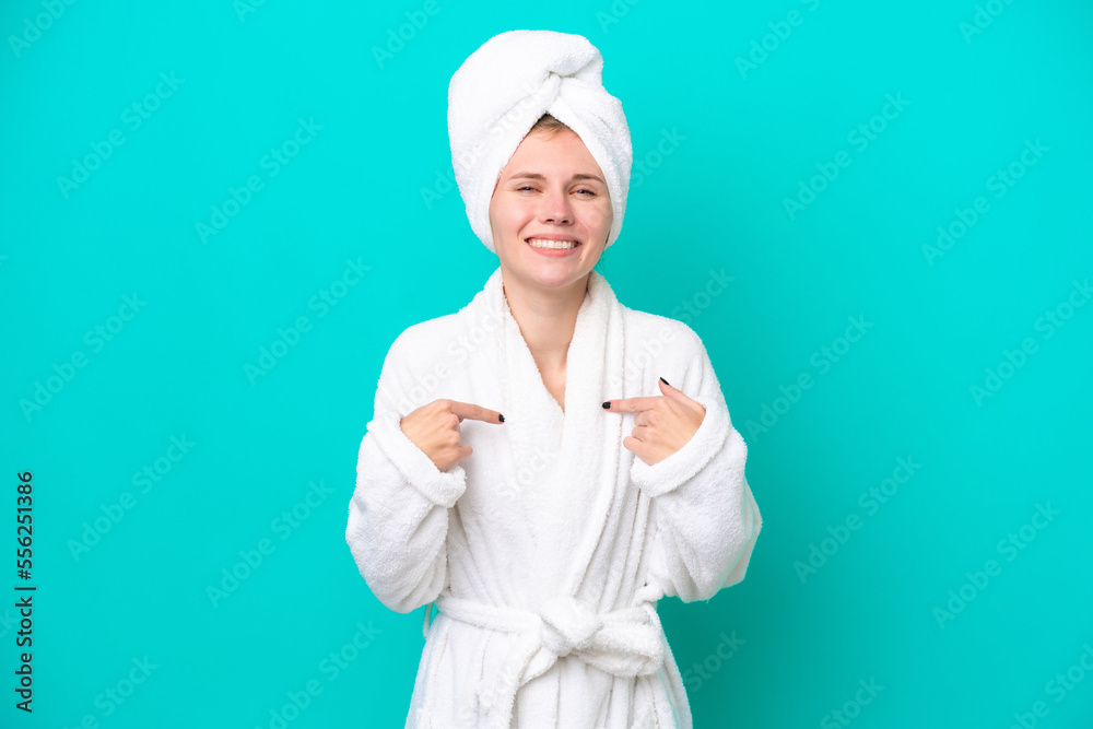 Young woman in a bathrobe isolated on blue background with surprise facial expression