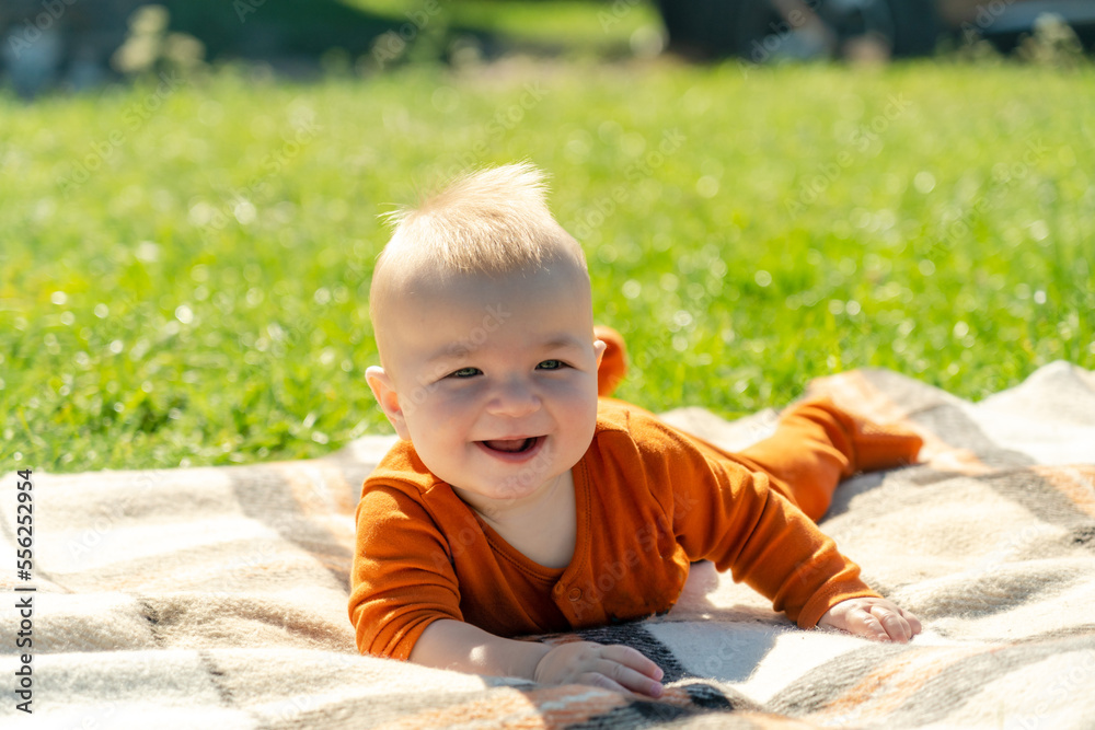 Happy baby lying on the blanket on sunny grass. Child outdoor. Happy baby lying on the blanket on sunny grass. Child outdoor.