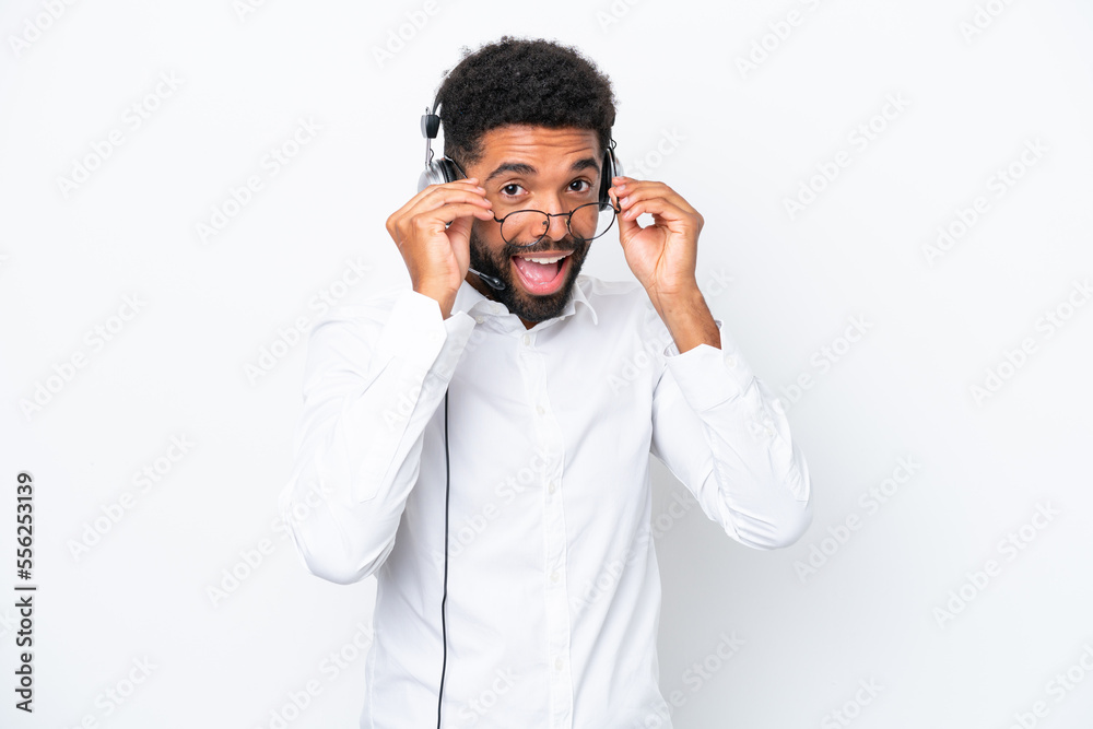 Telemarketer Brazilian man working with a headset isolated on white background with glasses and surprised Telemarketer Brazilian man working with a headset isolated on white background with glasses and surprised