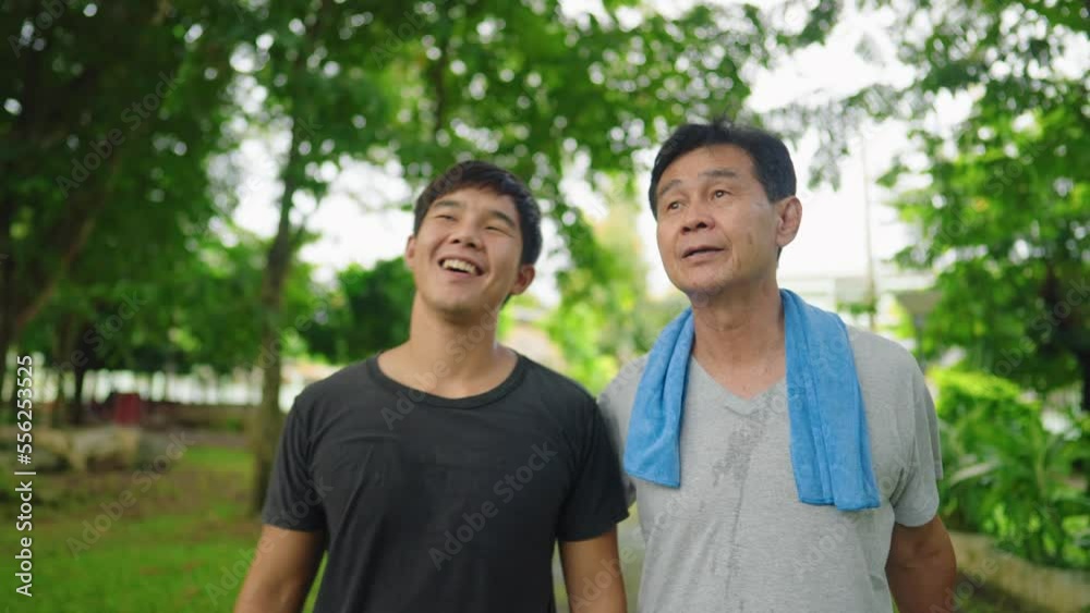 Close up a happy active asian father and adult son holding shoulder walking after jogging together. Relationship friendship between son and father. Recreation Lifestyle Leisure. Healthy Lifestyle Close up a happy active asian father and adult son holding shoulder walking after jogging together. Relationship friendship between son and father. Recreation Lifestyle Leisure. Healthy Lifestyle