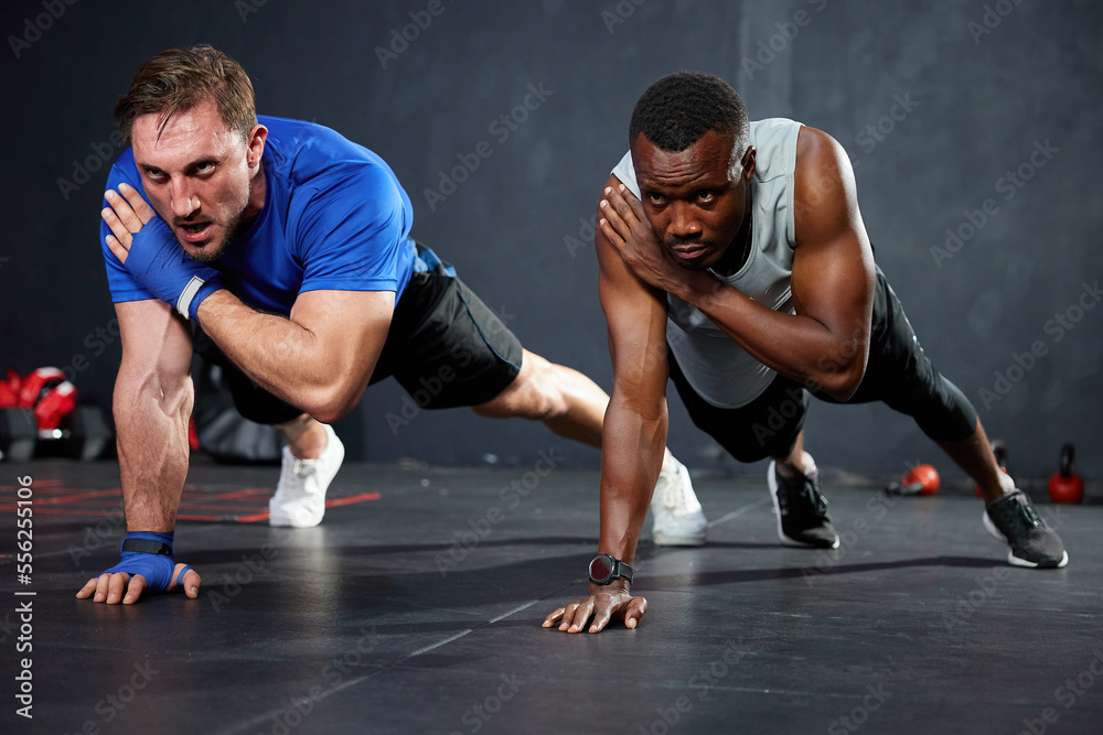 athletics men doing push up and touching shoulder with on the gym floor