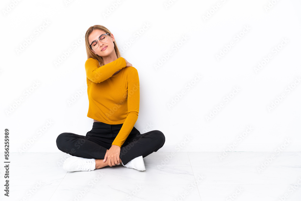 Blonde Uruguayan girl sitting on the floor suffering from pain in shoulder for having made an effort Blonde Uruguayan girl sitting on the floor suffering from pain in shoulder for having made an effort