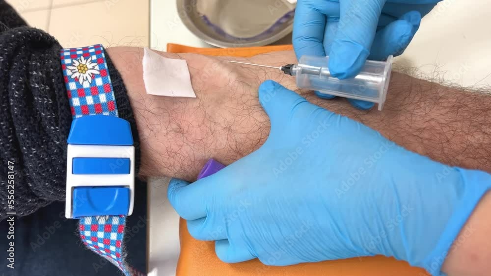 Nurse inserts needle into vein for drip infusion in hospital taking