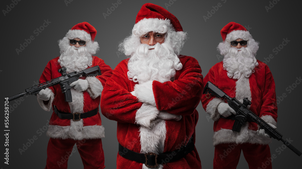 Studio shot of santa posing with crossed arms and two santa with rifles standing on his sides. Studio shot of santa posing with crossed arms and two santa with rifles standing on his sides.