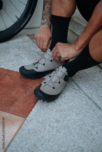 A bearded cyclist putting on socks and shoes for his morning bike ride