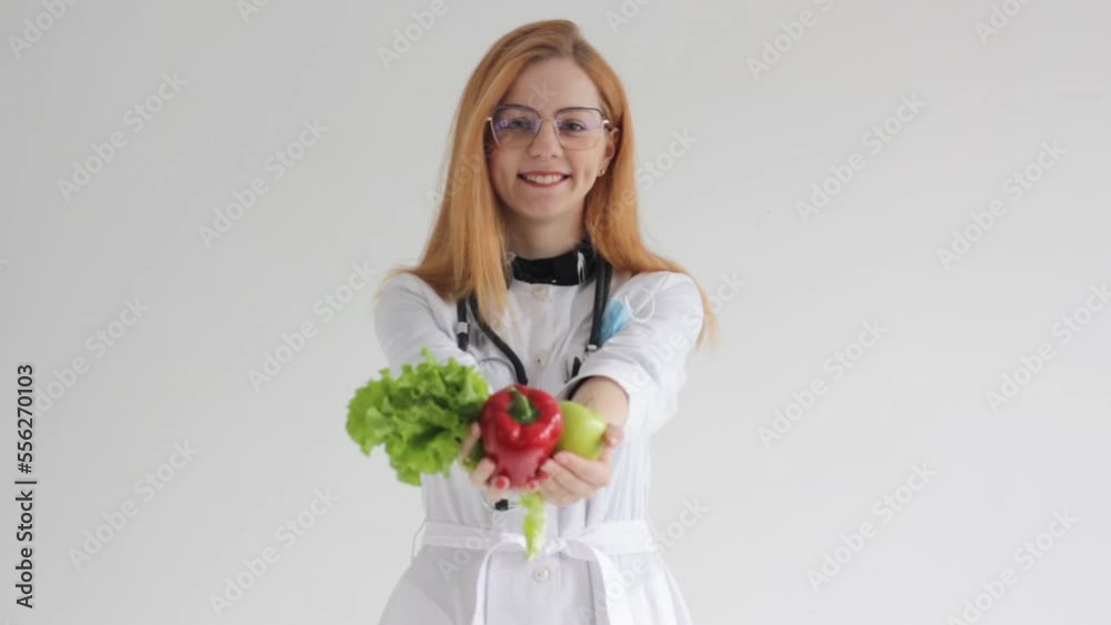Portrait of a beautiful smiling red-haired female doctor offering you vegetables healthy eating concept. Portrait of a beautiful smiling red-haired female doctor offering you vegetables healthy eating concept.
