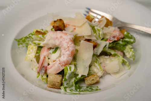 Cesar Salad with Prawns, Parmesan Shavings and Croutons and Garlic Dressing on a white Plate