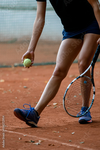 close-up shot of legs of woman tennis player with tennis racket and ball in her hand.