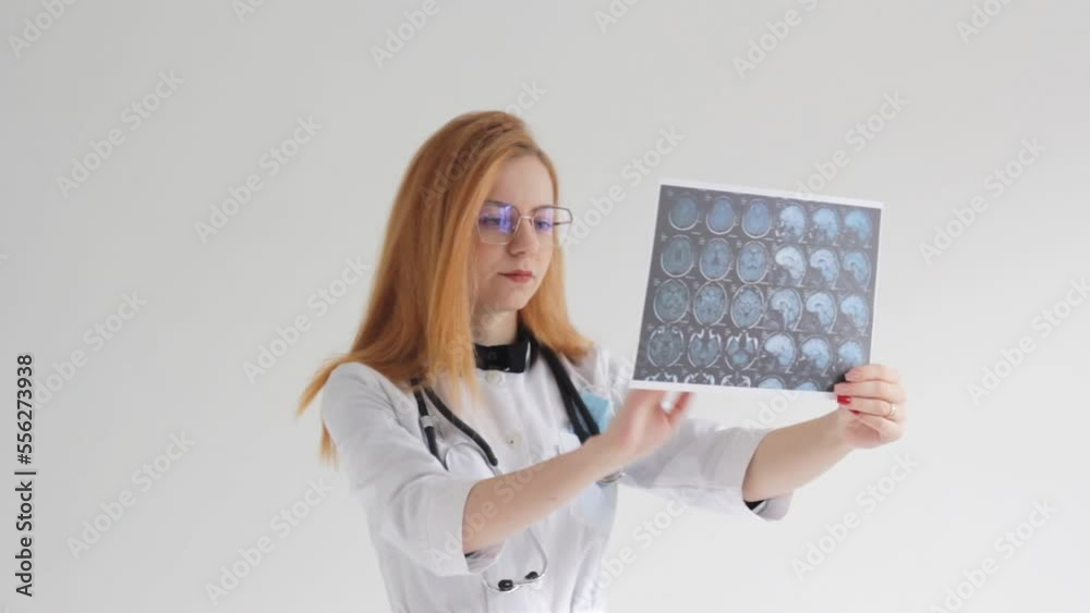 a young red-haired female doctor studies tomography images on a white background.