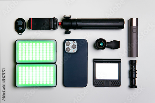 Equipment for shooting video on a smartphone. Microphone, LED lamp, tripod, lens smartphone are on a white table