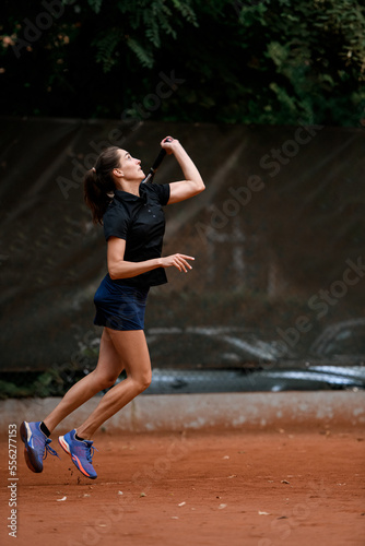 side view of an athletic female tennis player bouncing with racket and ready to hit tennis ball. © fesenko