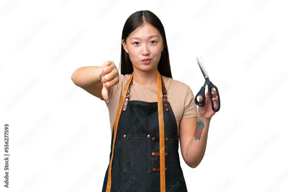 Young Asian seamstress woman over isolated background showing thumb down with negative expression Young Asian seamstress woman over isolated background showing thumb down with negative expression