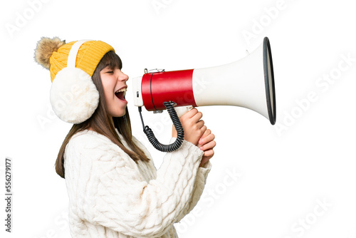 Fototapeta Little caucasian girl wearing winter muffs over isolated background shouting thr