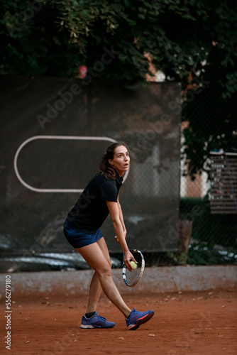 active woman tennis player with racket and ball prepares to serve at beginning of game © fesenko