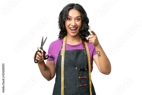 Young seamstress argentinian woman over isolated background surprised and pointing front