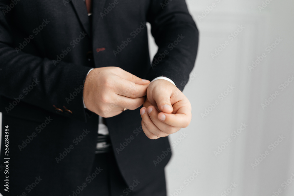 Close-up of a man in a suit adjusting a button on his shirt.The businessman adjusts the button on his white shirt. A cropped shot of a businessman in a suit adjusting cufflinks.