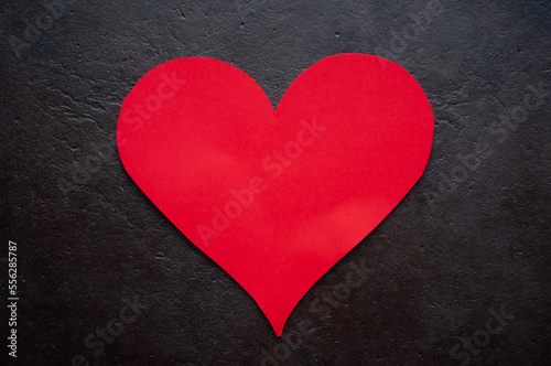 valentines day arrangement heart shaped piece of red card on black background as a gift to show love and affection for a specific person who they adore during the yearly special day 