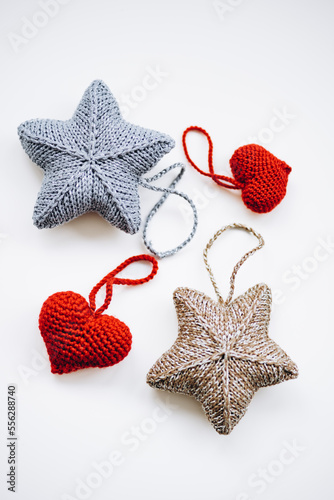 knitted decorations for the Christmas tree. handmade. do it yourself golden and silver stars and red hearts on a white background. place for writing. free space.