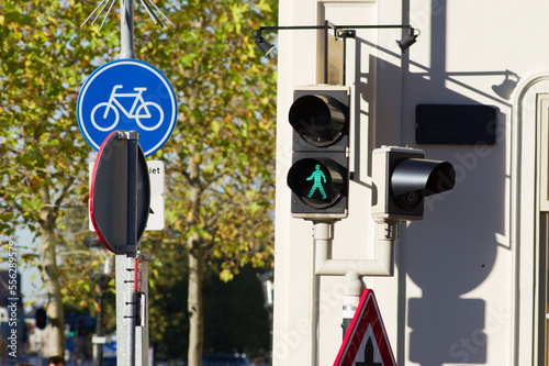 Pedestrian traffic light that turns green with traffic signs and a tree in the background in the Netherlands