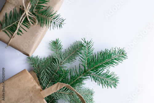 New Year s gift package made of craft paper  tied with a tourniquet  fir branches in a paper bag on a white background. Top view  place to copy