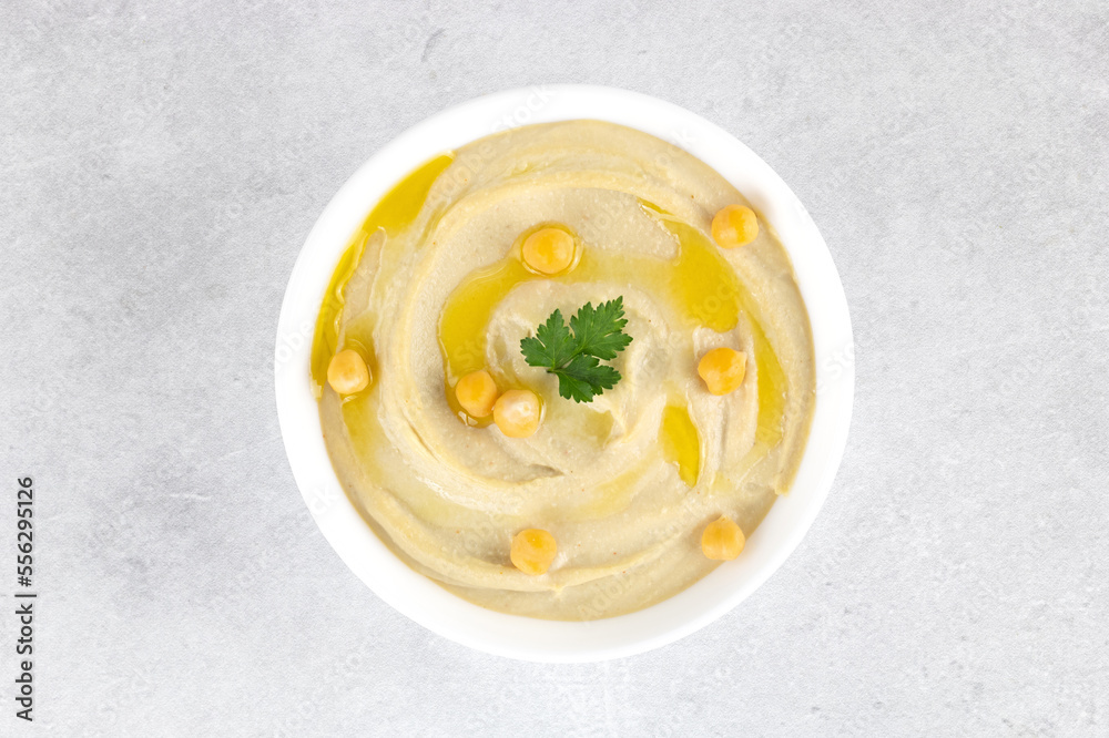 Classic hummus with parsley and olive oil in a plate on a gray background, top view. Arabic, Turkish cuisine. Classic hummus with parsley and olive oil in a plate on a gray background, top view. Arabic, Turkish cuisine.