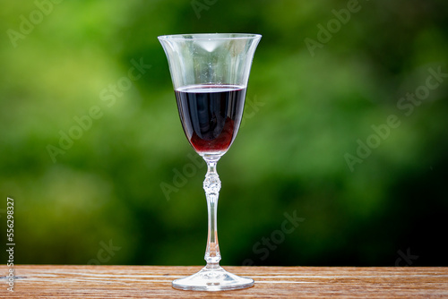 Glass of red wine isolated on rustic wooden table with blurred background