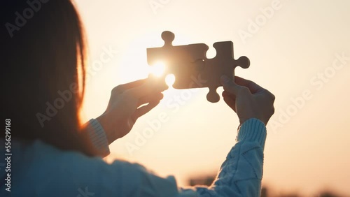 Closeup hands of woman connecting jigsaw puzzle with sunlight effect, Jigsaw alone wooden puzzle against sunset, Business solutions, Success and strategy concept photo