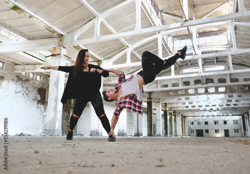 Boy and girl dancing hip-hop in old industrial building. Young couple training dance positions. Street urban lifestyle.