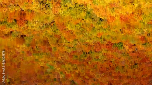 Autumn forest with a reflection on the restless surface of the lake 