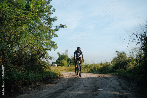 A young bearded cyclist is biking through a dirt path.
