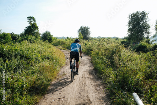 Fototapeta Naklejka Na Ścianę i Meble -  A young bearded cyclist is biking through a dirt path.