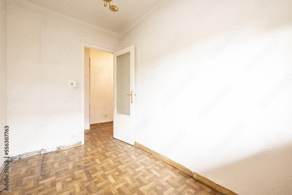 Empty living room with white walls with gotelé, wooden door with glass and without skirting