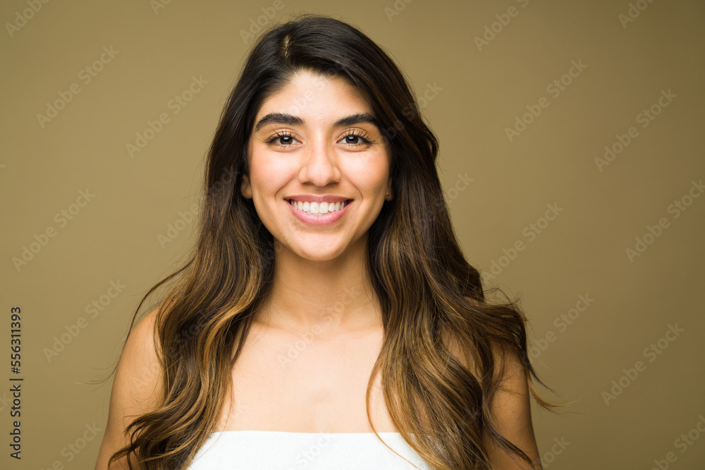 Portrait of an attractive mexican woman smiling and looking happy with clear beautiful skin and a beauty concept in front of a studio background Portrait of an attractive mexican woman smiling and looking happy with clear beautiful skin and a beauty concept in front of a studio background