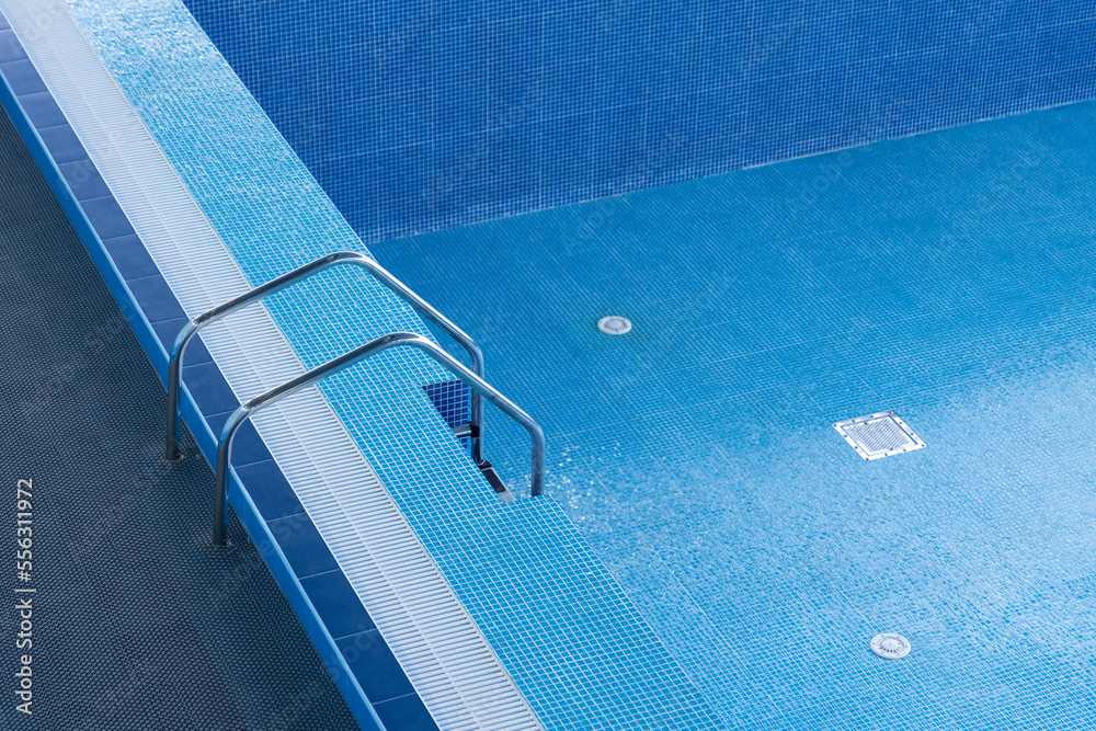 Large blue pool without water. Empty pool. Descent to a large swimming pool.  Empty swimming pool with descent down. Staircase leading to the pool.  Photos | Adobe Stock