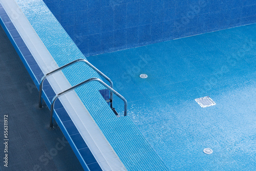 Large blue pool without water. Empty pool. Descent to a large swimming pool. Empty swimming pool with descent down. Staircase leading to the pool.