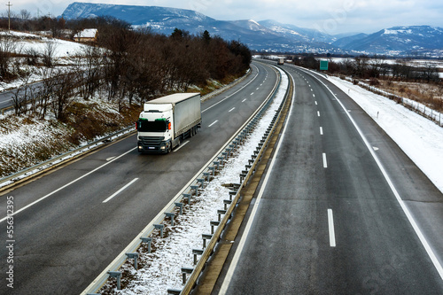 Single Lorry Truck on a Highway in a snowy winter landscape. Business Transportation And Trucking Industry. © Ivan