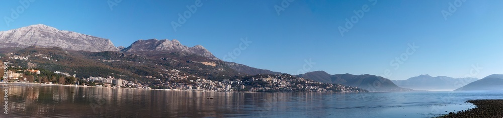 Autumn seascape harbor surrounded by mountains under blue sky wide panorama