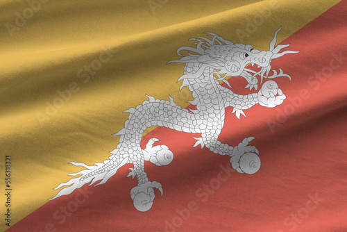 Bhutan flag with big folds waving close up under the studio light indoors. The official symbols and colors in fabric banner photo