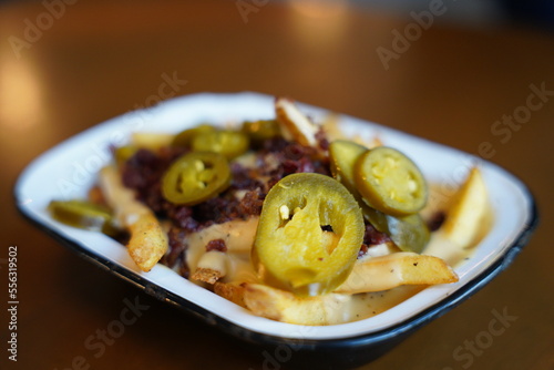 French fries with jalapeno and fried onion on top on a white plate restaurant. Section B.