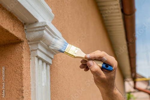 Obraz na płótnie house care The master uses white paint with a brush to paint the windows. close-up house repair w salonie