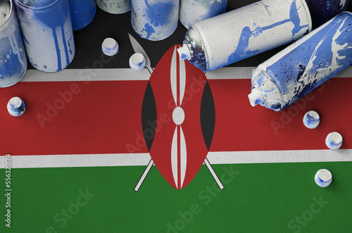 Kenya flag and few used aerosol spray cans for graffiti painting. Street art culture concept, vandalism problems photo