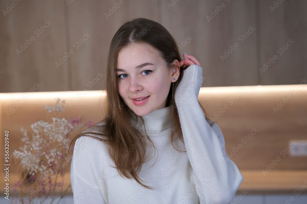 Portrait of young beautiful woman looking at camera at home at kitchen