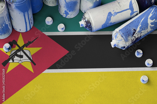 Mozambique flag and few used aerosol spray cans for graffiti painting. Street art culture concept, vandalism problems photo